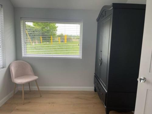 ein Schlafzimmer mit einem Fenster, einem Stuhl und einer Kommode in der Unterkunft Thimble Cottage in Buckinghamshire
