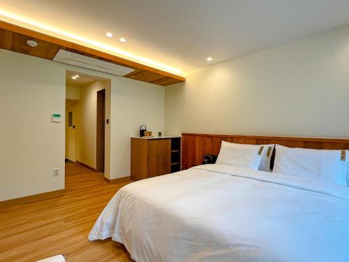 a bedroom with a large white bed with a wooden headboard at Hotel Ganwoljae in Ulsan
