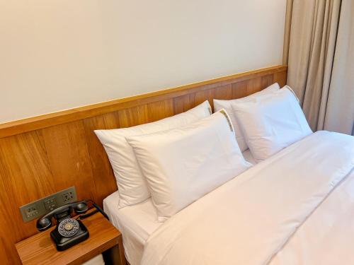 a bed with white pillows and a clock on a table at Hotel Ganwoljae in Ulsan