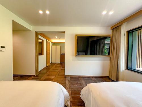 a bedroom with two beds and a television on the wall at Hotel Ganwoljae in Ulsan