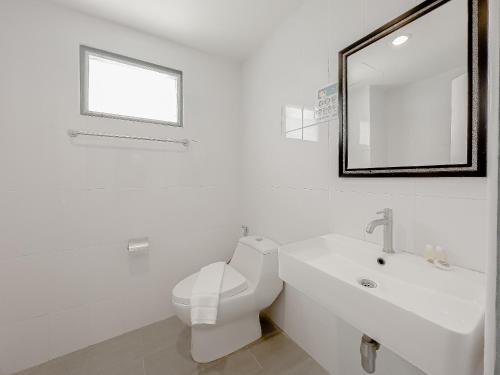 a white bathroom with a toilet and a sink at Xanadu Hotel Utapao in Rayong