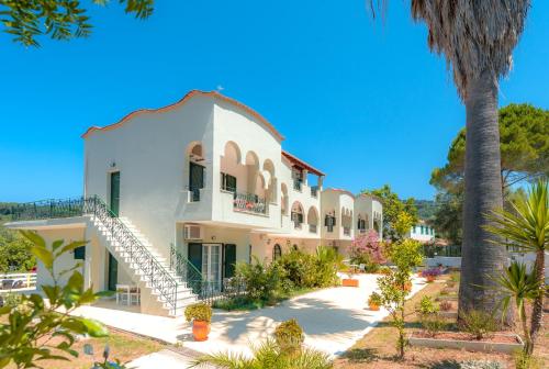 a large white building with a staircase in a yard at Vassilis Paradise Garden Aparthotel in Agios Georgios Pagon