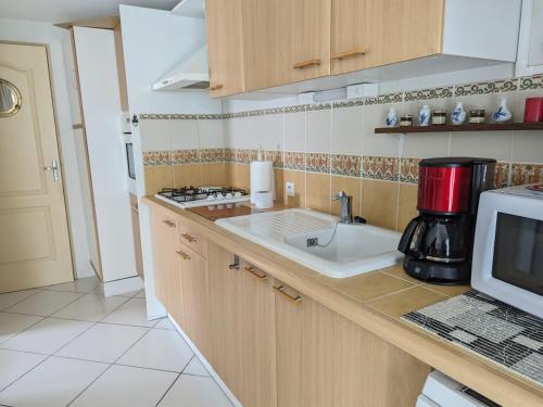 une cuisine avec un évier et un micro-ondes dans l'établissement Villa T3 Spacieuse à Port-la-Nouvelle – Jardin, Parking, à 900m de la Plage, Chien Admis - FR-1-797-50, à Port-la-Nouvelle