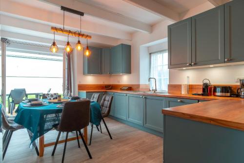 une cuisine avec des placards bleus et une table avec des chaises dans l'établissement Ma Kalon - Maison pour 8 avec parking, à Plomodiern