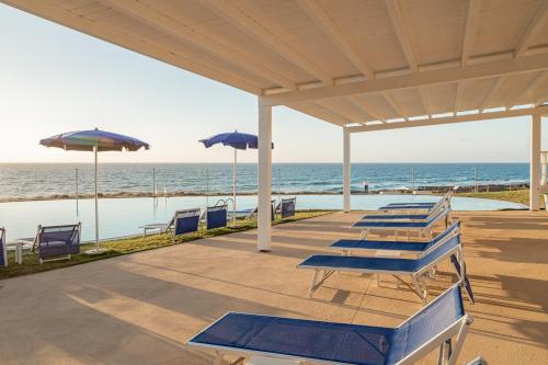 a row of chairs and umbrellas on the beach at Bellevue Sardinia Resort Affiliated by Meliá in Valledoria