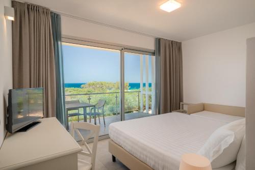 a hotel room with a bed and a view of the ocean at Bellevue Sardinia Resort Affiliated by Meliá in Valledoria