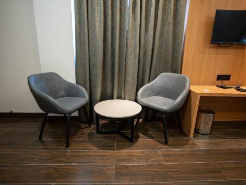 twee stoelen en een tafel voor een gordijn bij Pravasa Stay Near Luv Kush Square in Indore