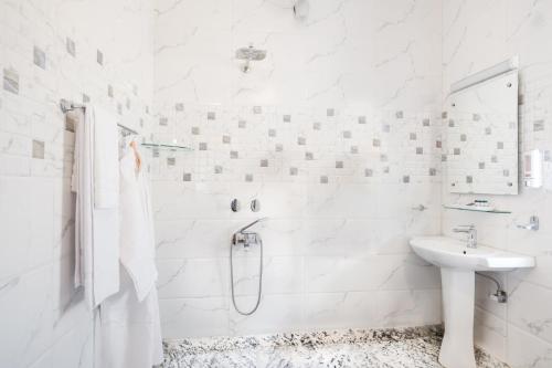 a white bathroom with a shower and a sink at Moghal Mahal Resort Rajbagh Srinagar in Rājbāgh
