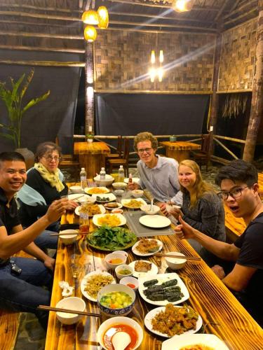 a group of people sitting around a table with food at Pu Luong Cuisine Garden Homestay in Làng Bang