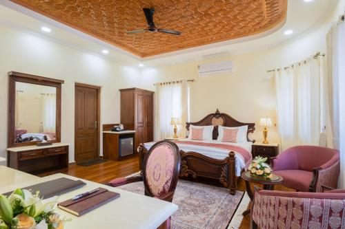 RājbāghMoghal Mahal Resort Rajbagh Srinagar的一间卧室，配有一张床、一张桌子和几把椅子