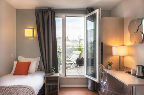 a bedroom with a bed and a window with a balcony at Dièse Hôtel Bastille in Paris