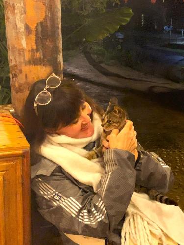 a woman is holding a cat in her lap at Pu Luong Cuisine Garden Homestay in Làng Bang