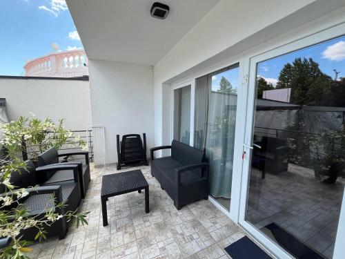 a patio with a couch and chairs on a balcony at City Apartman ház in Balatonlelle