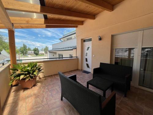 a patio with chairs and a table and a balcony at City Apartman ház in Balatonlelle