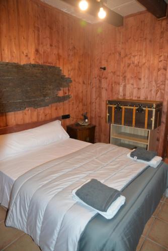 a bedroom with a white bed with wooden walls at Masía rural el Pati en Borredà in Borredá