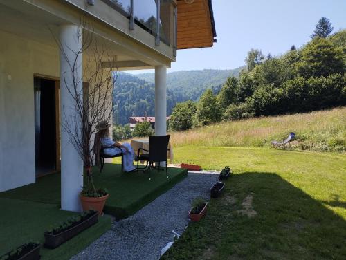 a woman sitting at a table on the porch of a house at ELFF -Apartamenty i pokoje gościnne in Cisna