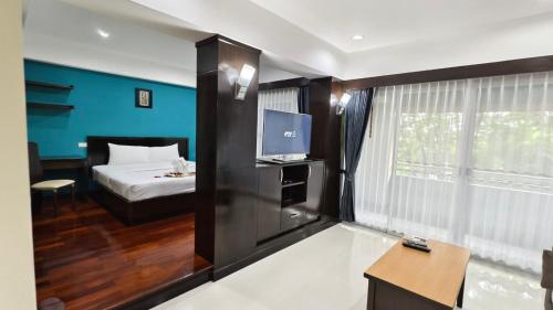 a room with a bed and a desk and a television at Eastpana Executive Residence 304 Prachinburi in Si Maha Phot