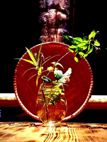 a red vase with flowers in it on a table at Pu Luong Cuisine Garden Homestay in Làng Bang