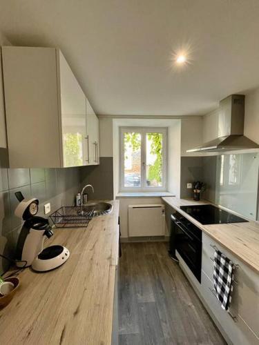 une cuisine avec des armoires blanches et un plancher en bois dans l'établissement T2- Le François III - Proche Centre ville, à Limoges