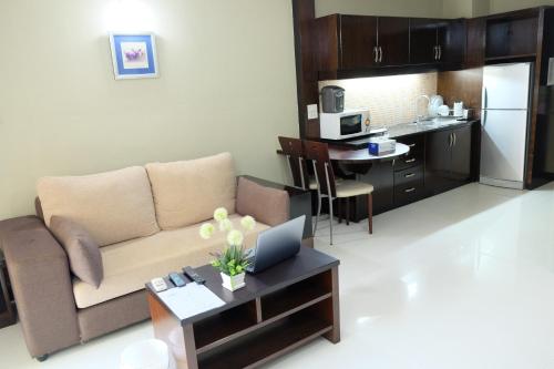 a living room with a couch and a table with a laptop at Eastpana Executive Residence 304 Prachinburi in Si Maha Phot