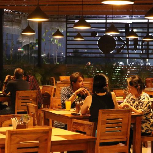 a group of people sitting at tables in a restaurant at Niko Hotels in Cochin