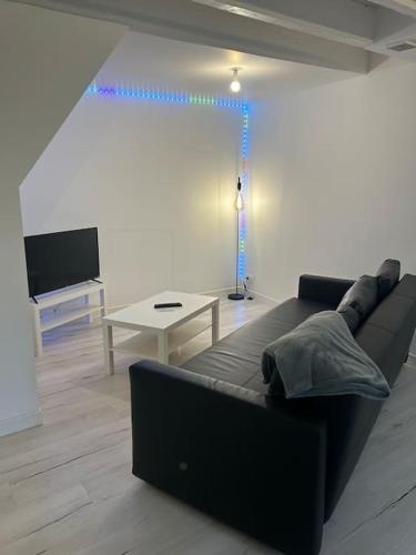 un salon avec un canapé noir et une table dans l'établissement Le Voltaire, à Dijon