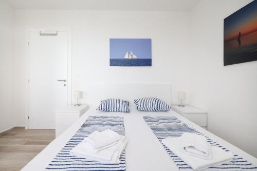 a white bed in a white room with two pillows at Villa Miri III in Privlaka