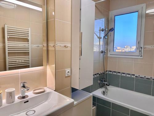 La salle de bains est pourvue d'un lavabo, d'une baignoire et d'une fenêtre. dans l'établissement 123 - Appartement spacieux pour 8 personnes à Paris, à Paris
