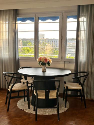 une table à manger avec des chaises et un vase de fleurs dans l'établissement 123 - Appartement spacieux pour 8 personnes à Paris, à Paris