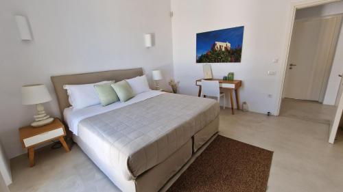 a bedroom with a large white bed and a desk at Sotavento Villa in Fanari