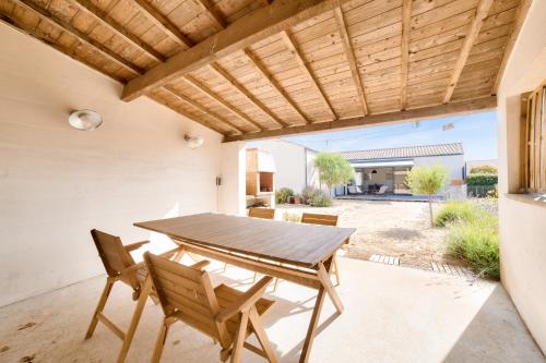une terrasse avec une table et des chaises en bois sous une pergola en bois. dans l'établissement Les Conches, Maison neuve pour 8, à Longeville-sur-Mer