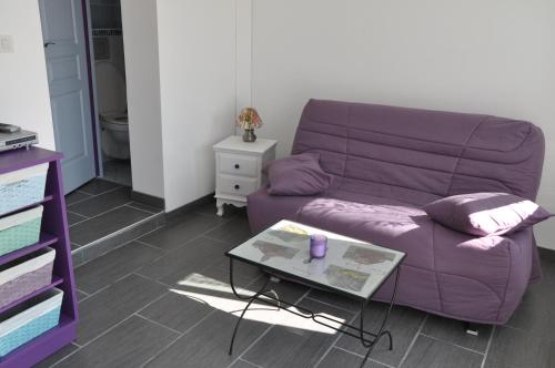 a purple couch in a living room with a table at Studio indépendant dans villa avec piscine à Gap in Gap