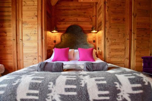a bedroom with a large bed with pink pillows at Chalet Valambrun - unashamedly luxurious Alpine living in Les Gets