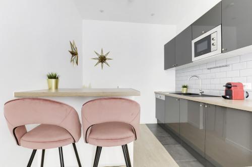 une cuisine avec deux chaises roses sur un comptoir dans l'établissement Nice Apartment Renovated And Bright Street Side, à Paris