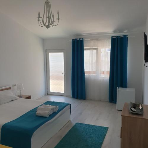 a bedroom with a bed with blue curtains and a window at Casa Happy in 2 Mai