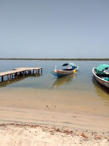 three boats sitting on the water next to a dock at Auberge Africa Thiossane in Saly Portudal