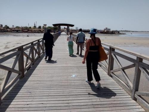 a group of people walking on a boardwalk on the beach at Auberge Africa Thiossane in Saly Portudal