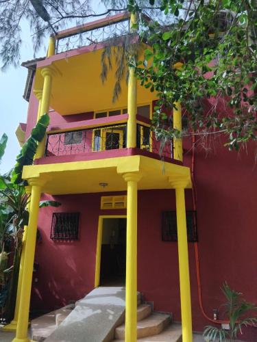 a red building with yellow columns in front of it at Auberge Africa Thiossane in Saly Portudal