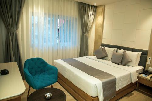 a bedroom with a large bed and a blue chair at Pan Asia Continental in Kolkata