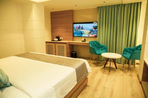 a hotel room with a bed and a desk and a tv at Pan Asia Continental in Kolkata