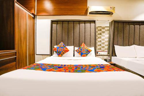a bedroom with a large white bed with colorful pillows at FabHotel Prime Welcome Palace in Surat