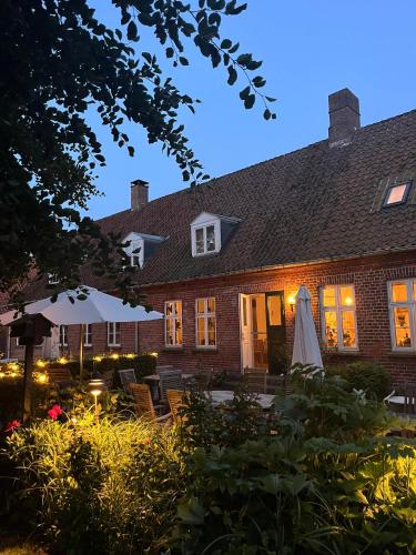a brick house with a patio and a white umbrella at Bellinge House in Horreby