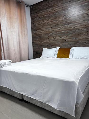 a bedroom with a large white bed with a wooden headboard at New apartment in Al Hoceïma