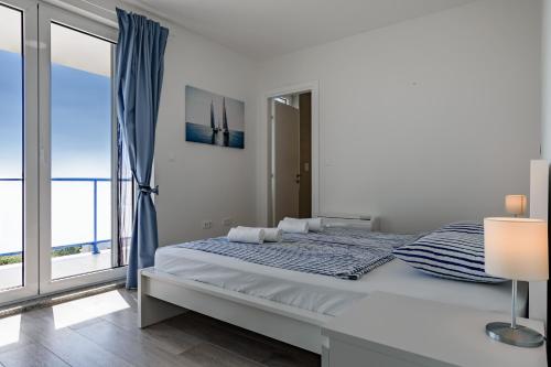 a white bedroom with a bed and a large window at Villa Miri III in Privlaka