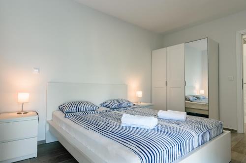 a white bedroom with a large bed with two pillows at Villa Miri III in Privlaka