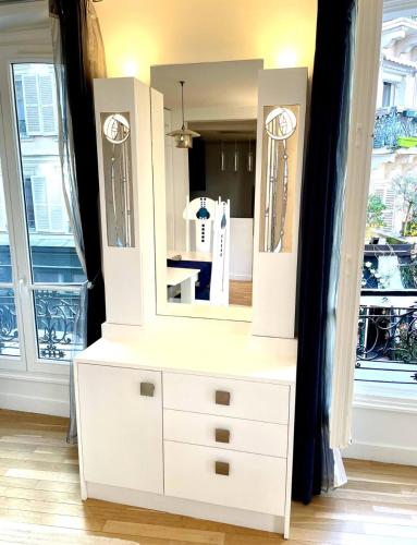 - une commode blanche avec un miroir au-dessus dans l'établissement Lovely Montmartre apartment, à Paris