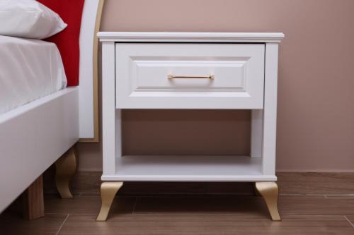 a white bedside table with a drawer next to a bed at Emar Hotel in Tirana