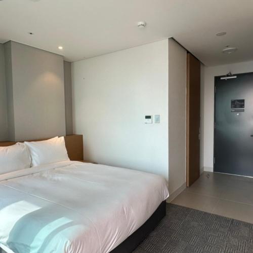 a bedroom with a large white bed and a door at Marysol by Haeundae beach in Busan