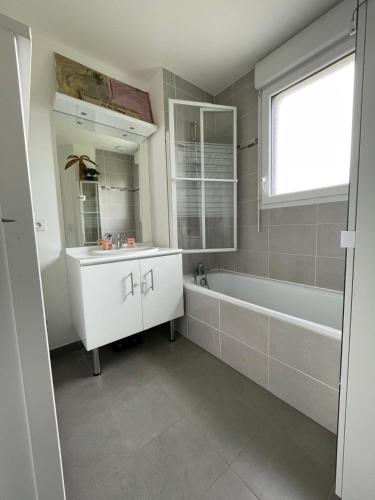 une salle de bain avec une baignoire, un lavabo et un miroir dans l'établissement Charmante Maison Piscine Privée, à Vert-Saint-Denis