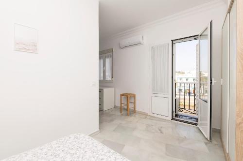 Dieses weiße Zimmer verfügt über ein großes Fenster und ein Bett. in der Unterkunft Verano en Chiclana in Chiclana de la Frontera
